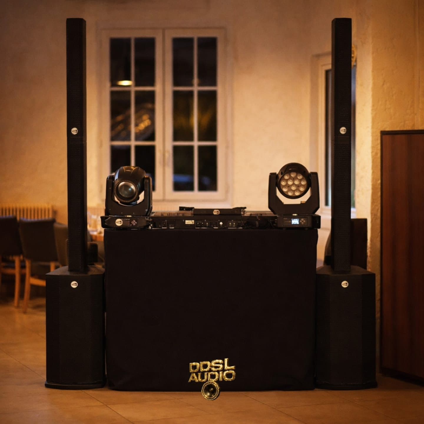 Régie DJ habillée aux couleurs de DDSL Audio, encadrée de deux colonnes acoustiques posées sur caissons de basse, avec deux lyres installées sur la régie.